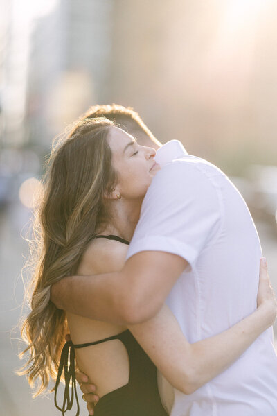 This heartwarming image captures a fiancé hugging his partner from behind during a winter photo shoot on Lake Louise. The snowy landscape and icy backdrop enhance the warmth and closeness of their embrace, encapsulating a perfect moment of love and connection in the chilly setting.