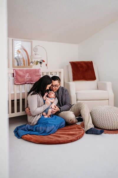 a new family of 3 cuddles in their baby's nursery