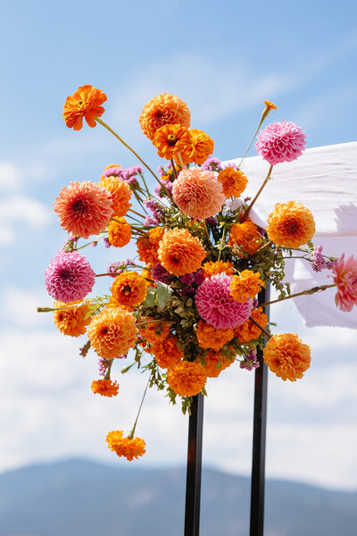 Luxury wedding design details for a Colorado mountain wedding. Bright orange and pink florals 