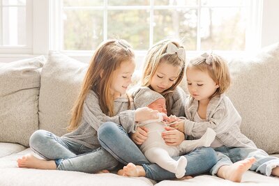 Sisters hold baby brother during in home newborn photo session with Sara Sniderman Photography  in Sherborn Massachusetts