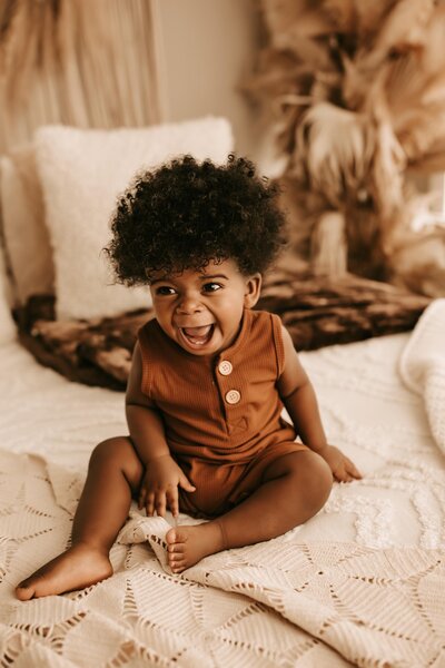 Adorable child in rust-colored outfit with big smile during a milestone photography session in Memphis