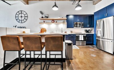 Bar height seating for three in the kitchen of this three-bedroom, two-bathroom industrial modern loft condo in the historic Behrens building in downtown Waco, TX.