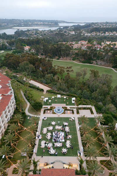 Drone overhead shot of a beautiful garden courtyard reception space with a dance floor and al fresco dining tables surrounding it.