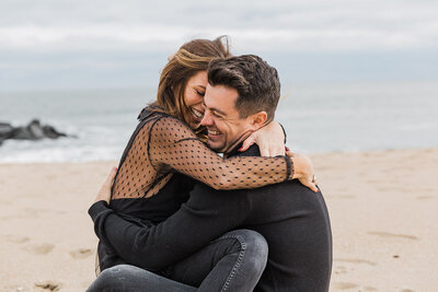 Couple hugs and laughing while  at the beach for a photography session