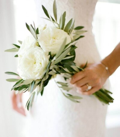 Bride holding small bouquet of white florals