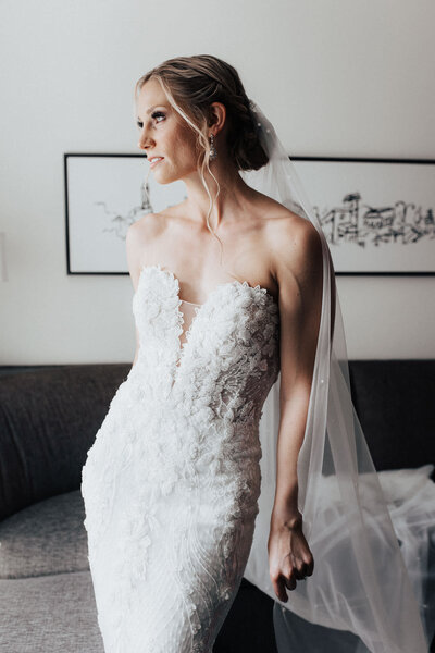 Bride after getting into her elegant , mermaid shaped wedding dress in hotel room. Dress with lace and sweetheart neckline.