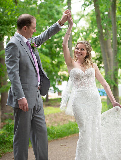 groom twirls bride on treelined street