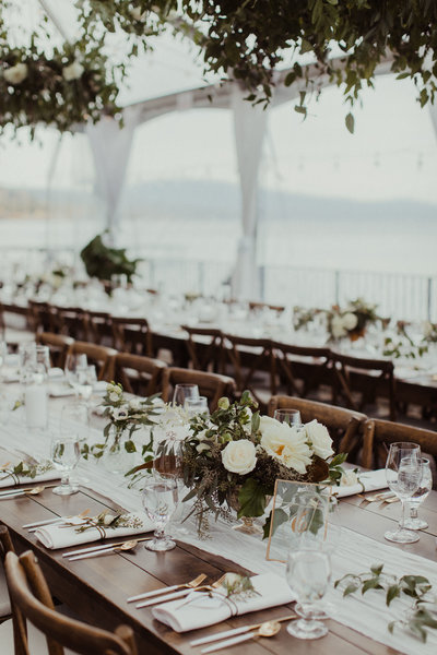 wedding reception tables with silverware and glasses and white flowers in vases