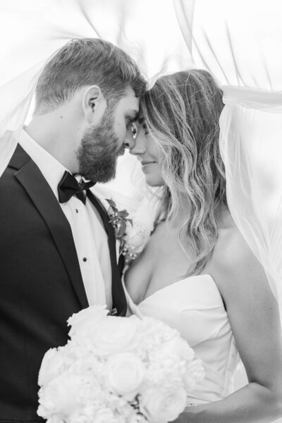 Black and white photo of bride and groom touching noses and looking into eachothers eyes