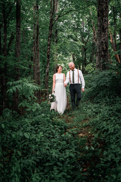 bride and groom waling through lush greenery in the woods by North Conway NH by Lisa Smith Photography