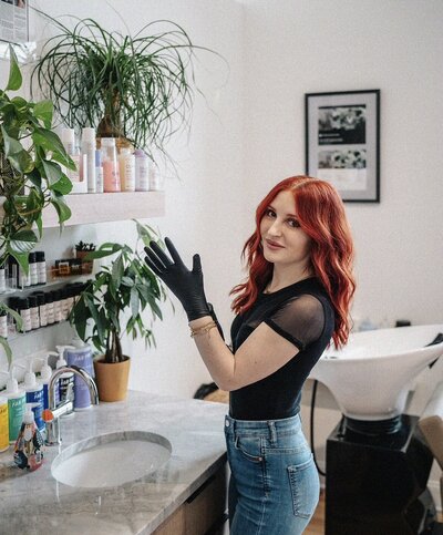 Woman with red hair and tattoos holding a hair color brush