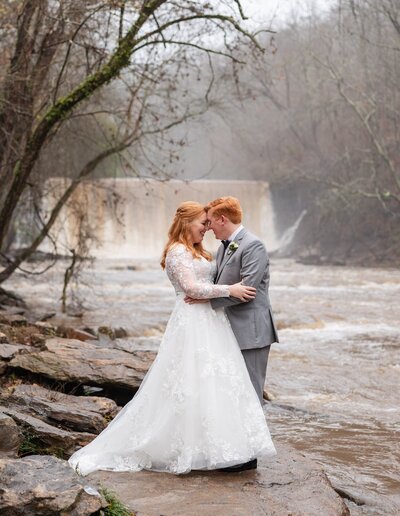 bride and groom embracing by the water