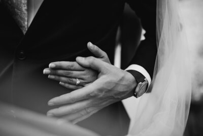 Black and white photo of bride holding her dress facing away from camera