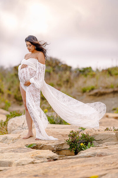 pregnant woman holding belly in ocean maternity shoot