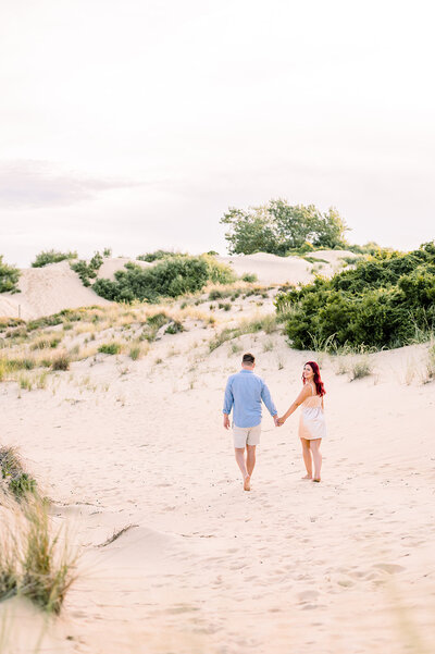 wedding couple laughing holding hands in greenery