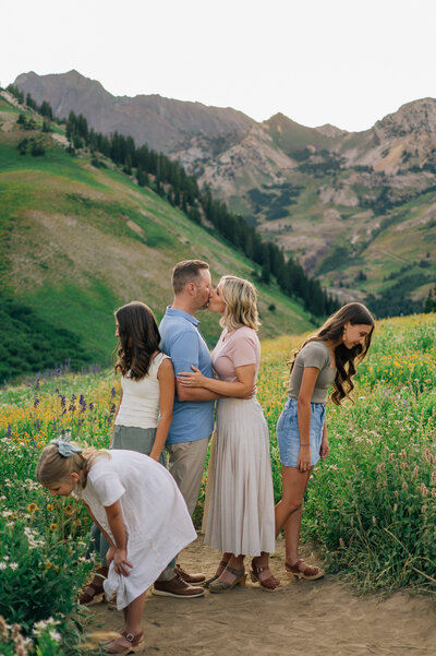 Couple kissing while kids are looking at flowers in Little Cottonwood Canyon, Utah