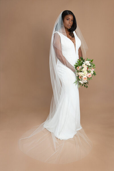 bride wearing a chapel length veil and holding a white and blush bouquet