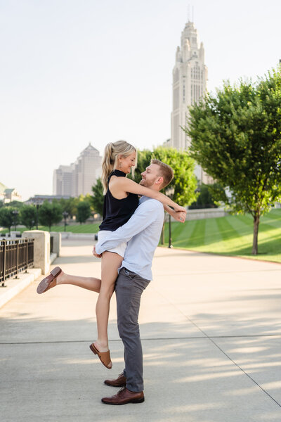 A young man lifts his fiance along the Scioto Mile in Columbus Ohio