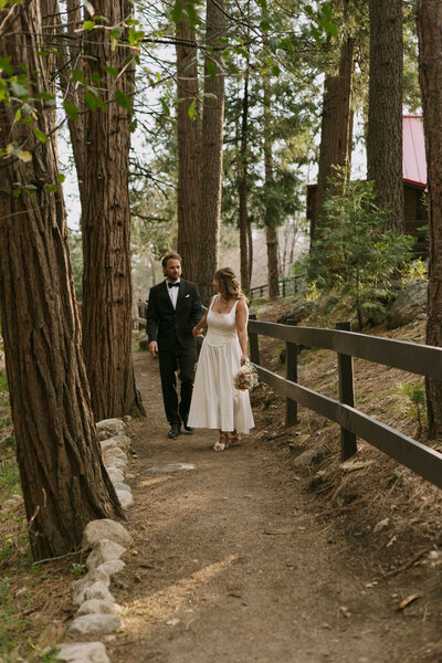 Bride and groom walking down a pathway in the trees in Idyllwild California.