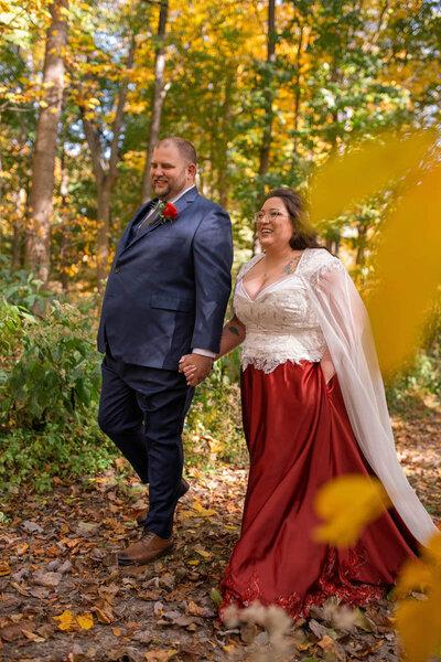Bride and groom walk together on a beautiful autumn day with brightly colored leaves