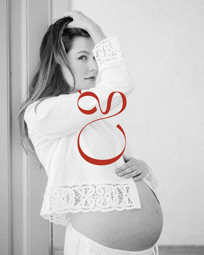 Black-and-white image of a pregnant woman cradling her belly, accented by a small red logo submark.