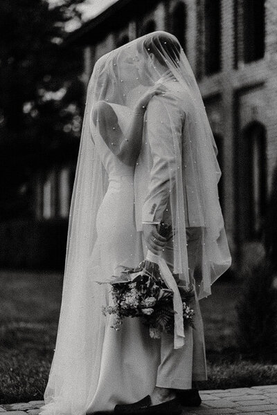 Bride and groom kissing under veil