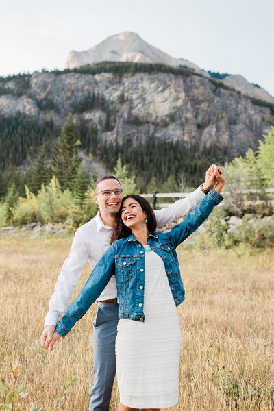 Couple dancing in field in front of mountains