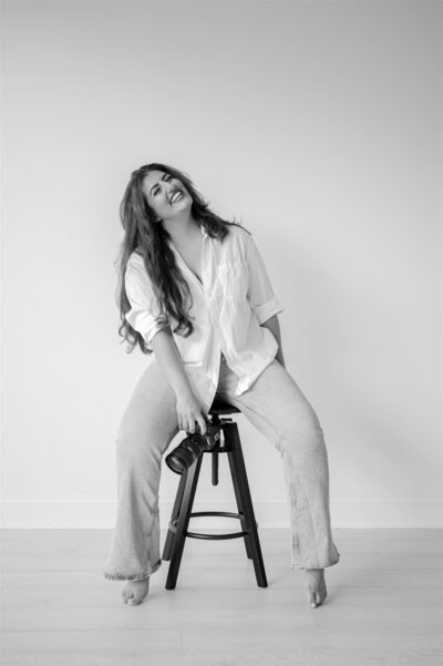 Black and white portrait of Hiba, Raleigh-based creative behind Moments by Hiba, holding a camera and laughing during branding session.