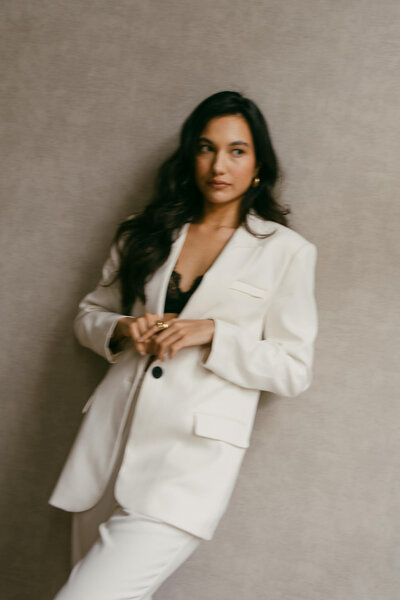 Een model leunt met haar schouder tegen de muur en kijkt denkelijk een kant op. Haar handen elegant bij elkaar en een sterke blik, vastgelegd door Sharon Kastelijns Photography.