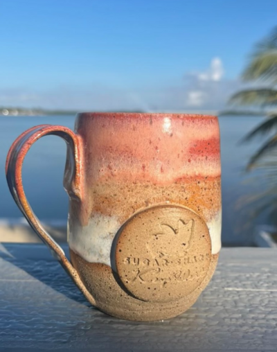 A table inside of Sacred Space Gallery in Key West, Florida displays fruit bowls, mugs, oil bottle and plates made by Jill Marie Pottery alongside other artwork by woman artists residing in Key West, FL