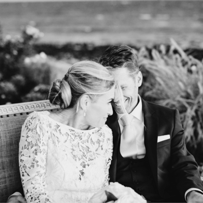 Black and white photo of bride and groom sitting and laughing