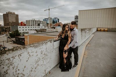 Engaged couple standing on London, Ontario rooftop parking deck for engagement photos