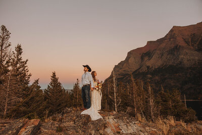 bride and groom posing on mountainside