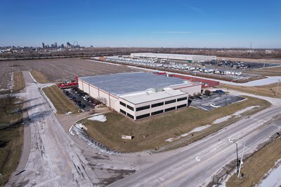 Drone photograph of an industrial building with vacant land and a large warehouse behind it. In the background you can see downtown St. Louis.