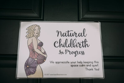 Sign reading “Natural Childbirth in Progress” requesting quiet and calm during home birth
