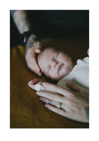 Parents with hands placed on newborn babies head and arm