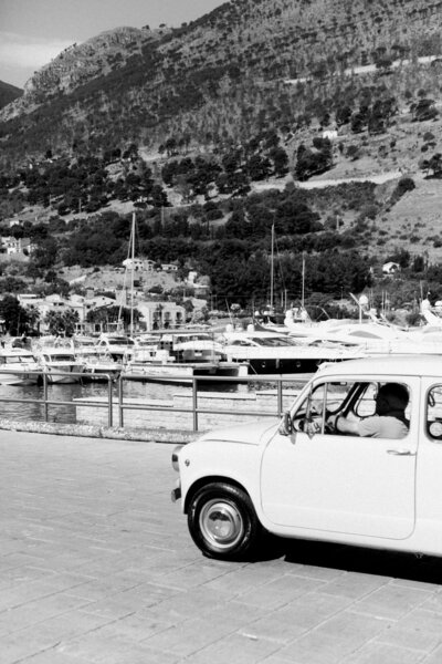 Classic white Fiat parked at an Italian marina — symbolizing the timeless elegance of European travel experiences.