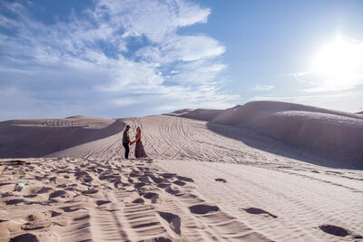 engaged couple walks in yuma sand dunes