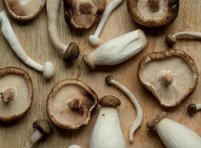 Close-up flat lay of fresh mushrooms on a rustic wooden table, symbolizing natural, wholesome ingredients for a healthy lifestyle.