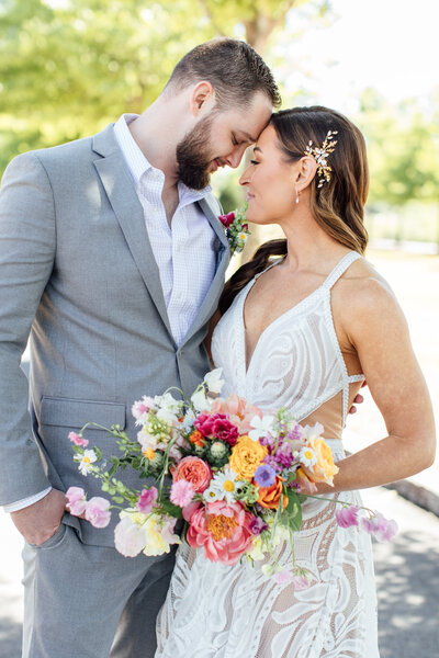man in grey suit looking at woman in white dress holding a bouquet of flowers
