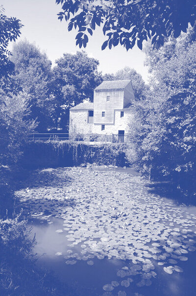 Moulin à eau du Moulin de rambourg avec étendue d'eau recouverte de nénuphars au premier plan. Monochromie en bleu et blanc.