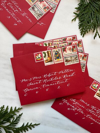 Red envelopes with white ink calligraphy  and vintage Christmas postage stamps