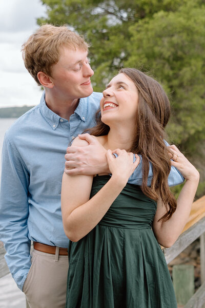 Engaged couple laughs on the shore of Lake Wylie