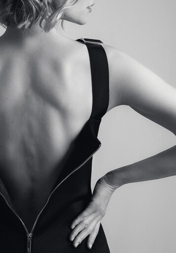 Back portrait of a woman in an unzipped black dress.