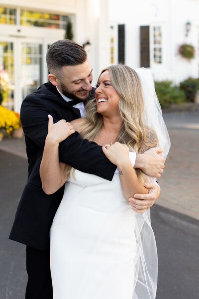 Groom is hugging bride from behind as they gaze into each other's eyes