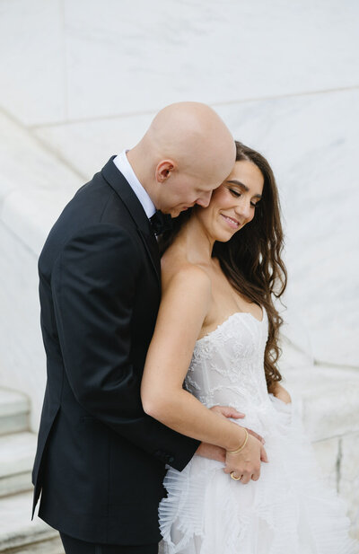 bride and groom embrace in front of the entrance of Meadow Brook Hall in Rochester Hills, MI
