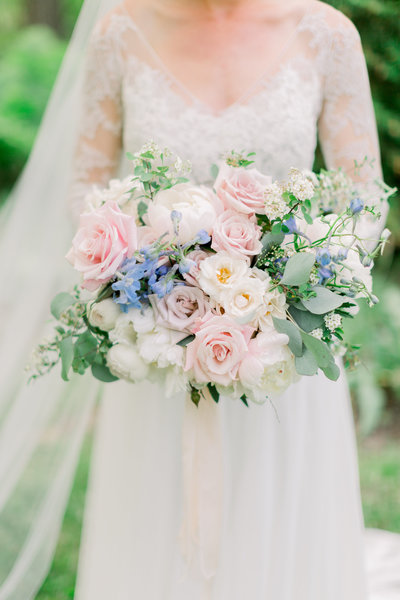 Photo of a soft pastel inspired bouquet with pinks, light blues, and white flowers.