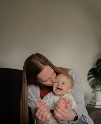 mother holding infant child and kissing his cheek
