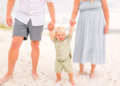 Little boy plays with parents ont he beach