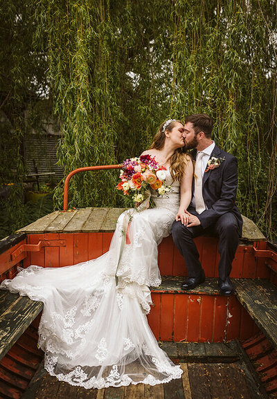 Bride holding colourful bouquet sharing a kiss with her husband